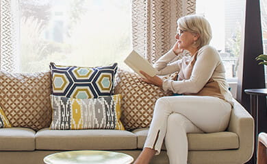 Woman reading book on modern living room sofa
