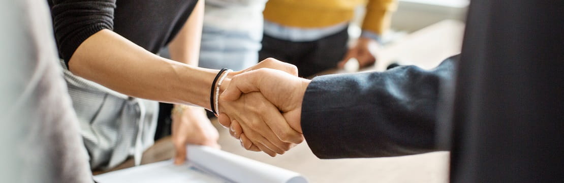 Two professionals shaking hands in a business setting.
